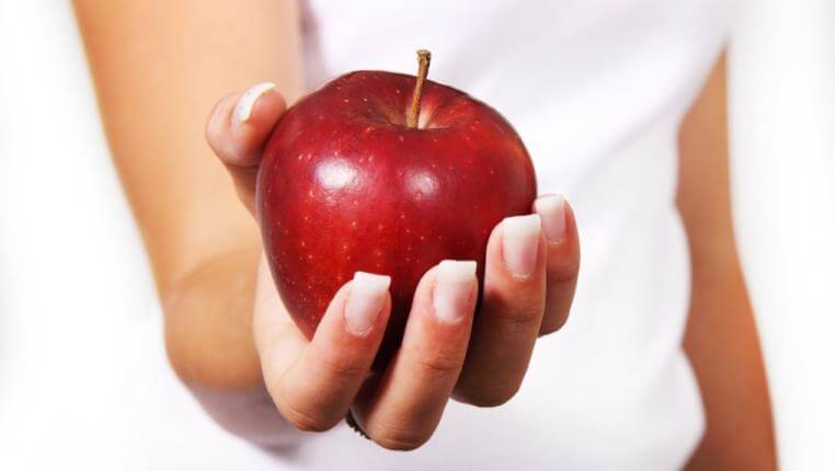 lady at an office holding a heathly red apple